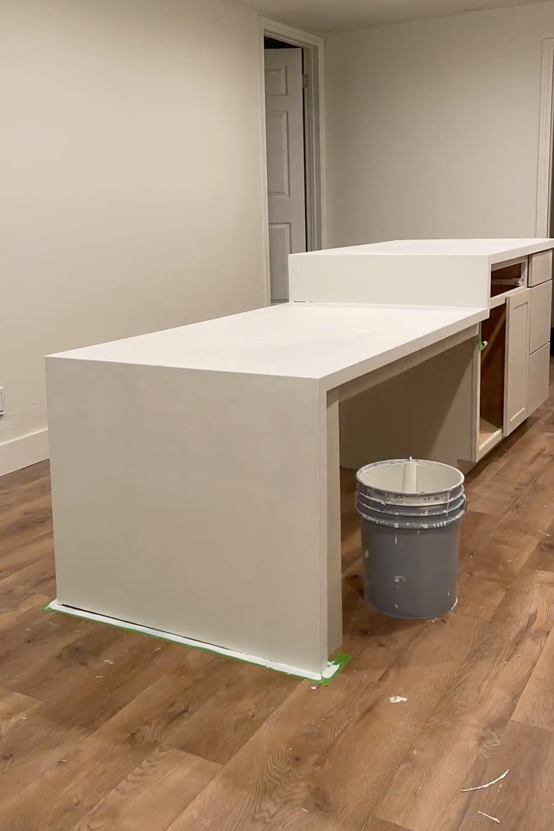 A faux marble waterfall kitchen island after being primed.